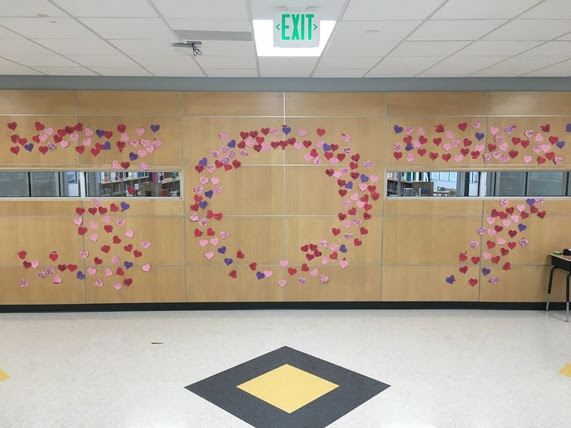 A wall in Meadowlark Elementary school is covered with hearts in the shape of the numbers "307". Each of the hearts has a random act of kindness written on it.