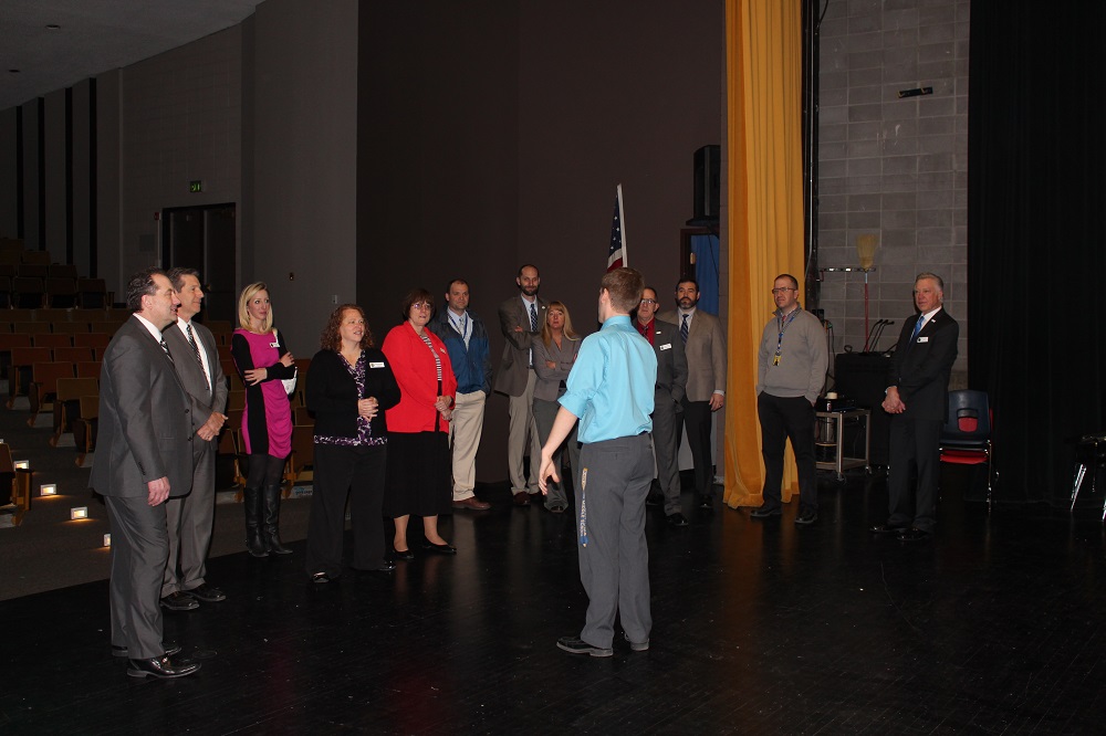 Members of the State Board and WDE staff stand on the stage of the auditorium at Wheatland high school as music teacher Mr. Bradley explains the upgrades made to the lighting system through a grant administered by the WDE.