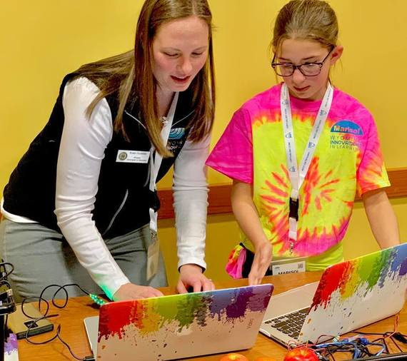 A WDE employee helps a jr. high student navigate a project on a laptop during the Innovations Conference.