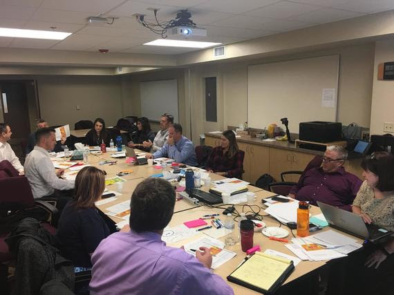 About a dozen Wyoming Department of Education staff sit around a conference table working during a meeting.