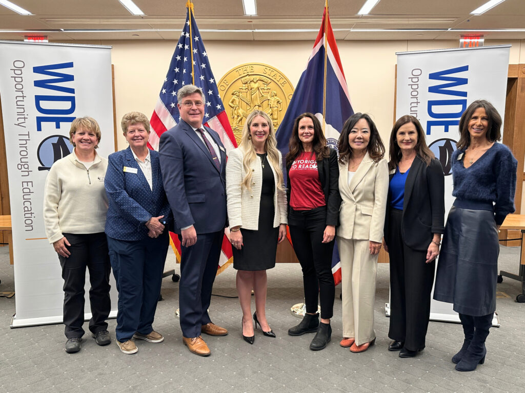 Partners of the statewide Language and Literacy Initiative pose for a photo in front of flags and banners.